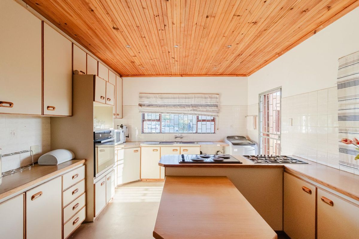 A functional kitchen featuring wooden ceiling paneling, built-in cabinetry, a gas hob, and an integrated oven, offering a practical layout for daily meal preparation.