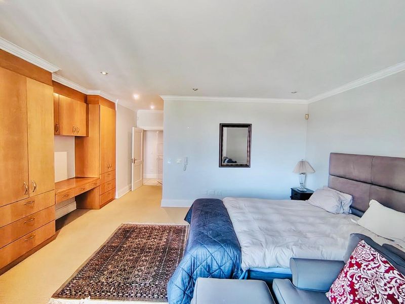 Spacious bedroom featuring extensive built-in wooden cabinetry and a integrated desk area, complemented by recessed lighting and crown molding.