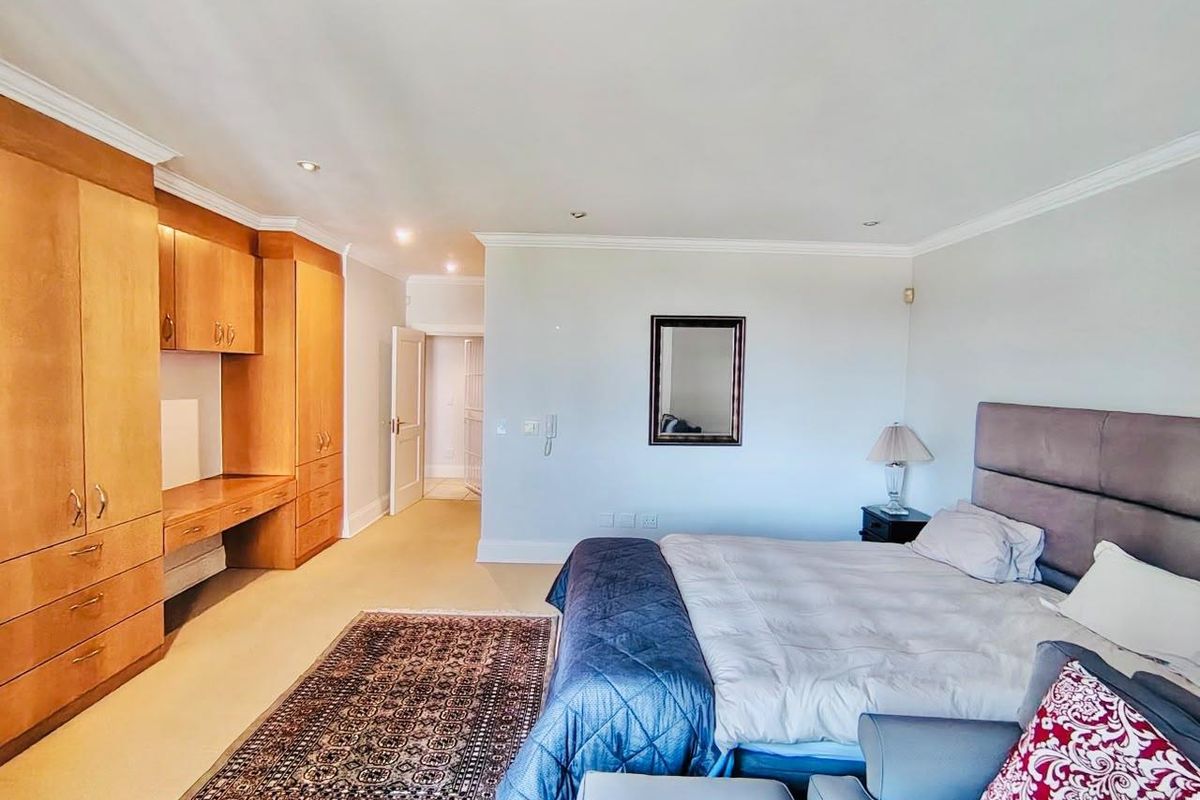 Spacious bedroom featuring extensive built-in wooden cabinetry and a integrated desk area, complemented by recessed lighting and crown molding.