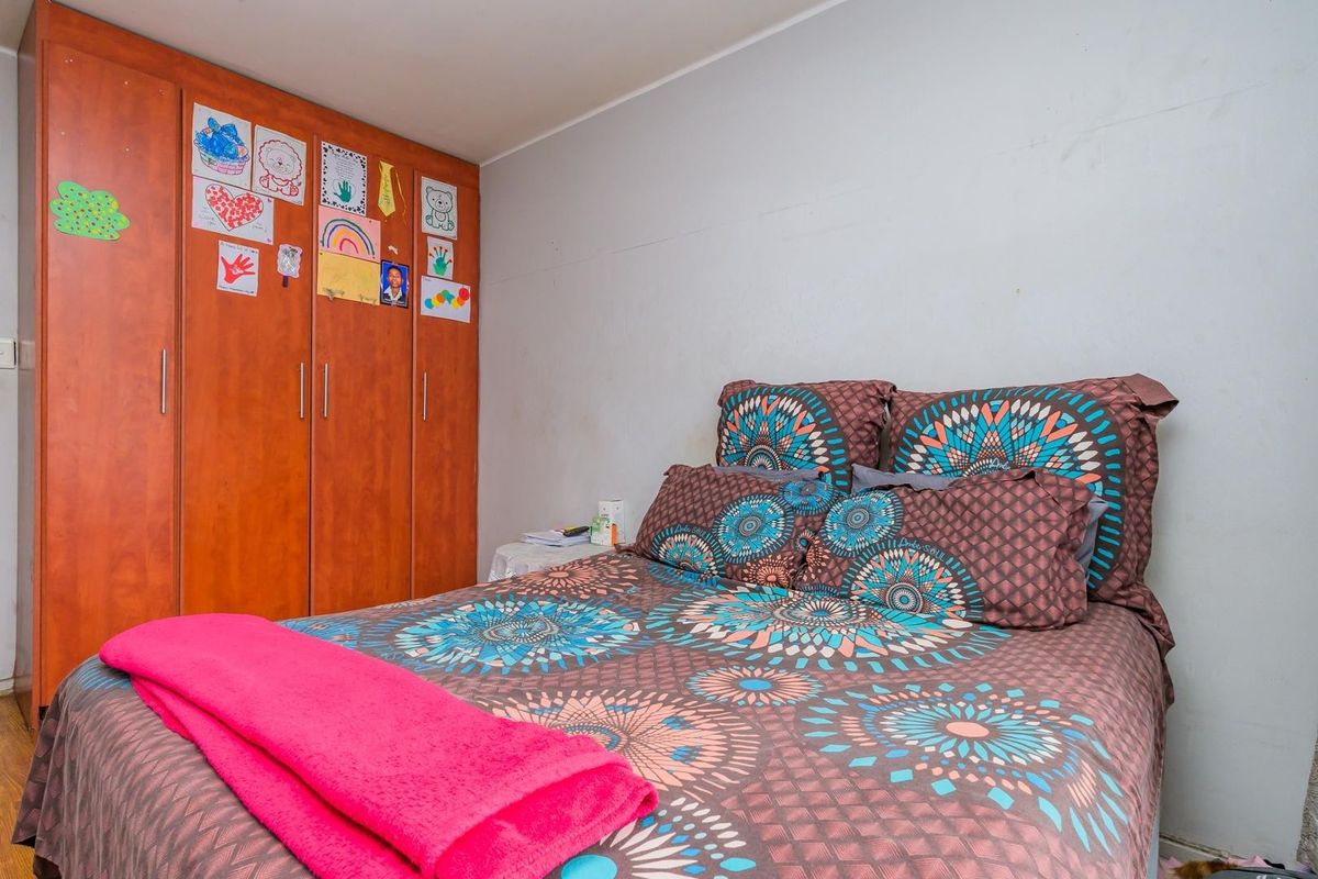 A bedroom featuring a built-in wooden wardrobe with ample storage space.