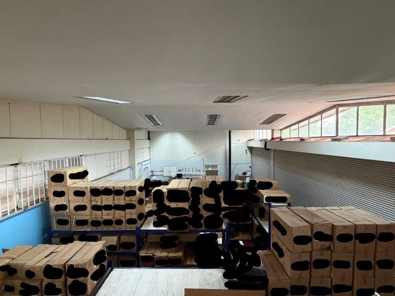 A large industrial utility or storage space featuring high ceilings, clerestory windows, and integrated roller shutter doors for access.
