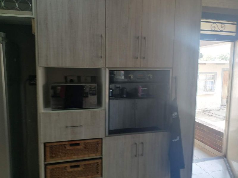 A kitchen area featuring light-toned wood-look built-in cabinetry with an integrated oven and microwave unit, providing functional storage and cooking space.