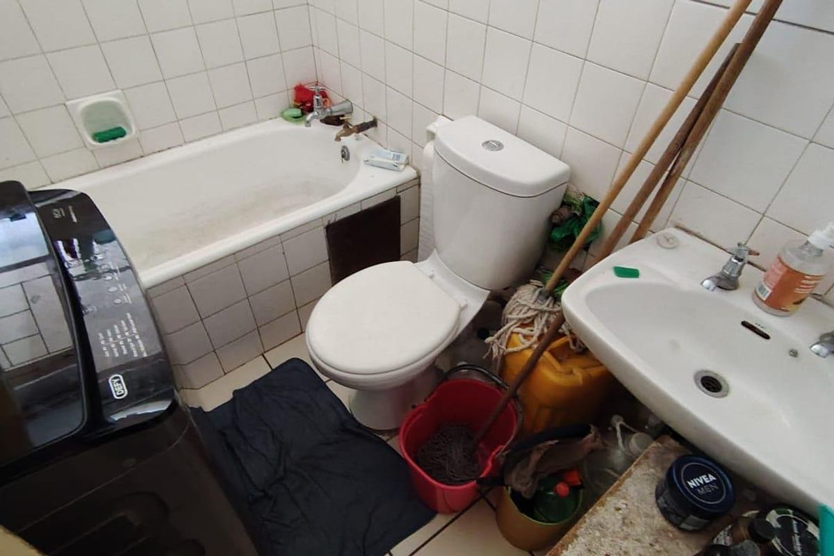 Compact bathroom featuring a bathtub, toilet, and washbasin with white wall tiling. The space requires cosmetic updates to improve its overall condition.