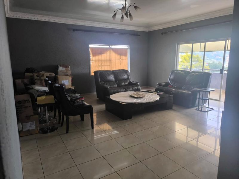 Spacious living room featuring large format floor tiles, decorative ceiling cornicing, and a sliding glass door providing access to an outdoor area.