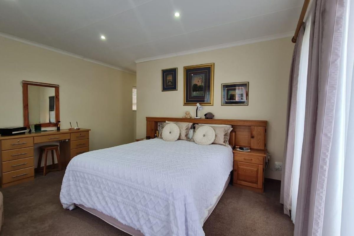 A well-maintained bedroom featuring neutral wall tones, carpeted flooring, and recessed ceiling lighting, providing a comfortable and functional living space.