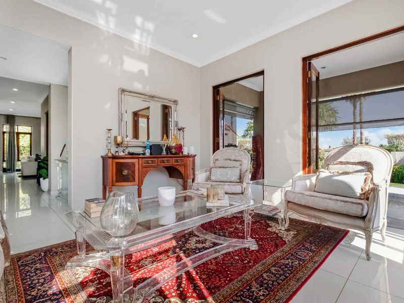 Bright living room featuring polished tiled floors, elegant cornicing, and double doors providing seamless access to the outdoor patio area.