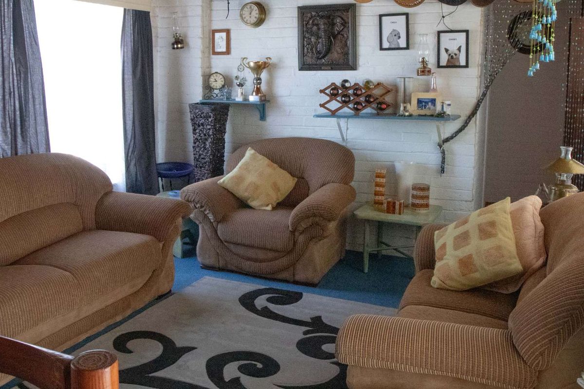 A cozy living room featuring painted brick walls and large windows, providing a comfortable and inviting space for relaxation.