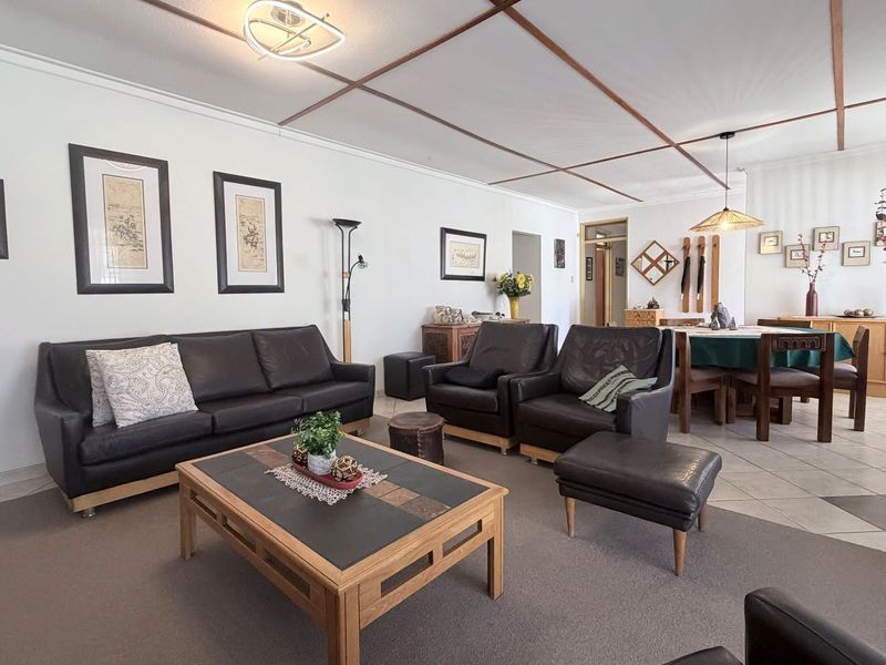 Spacious open-plan living and dining area featuring a combination of tiled and carpeted flooring with a distinctive grid-patterned ceiling.