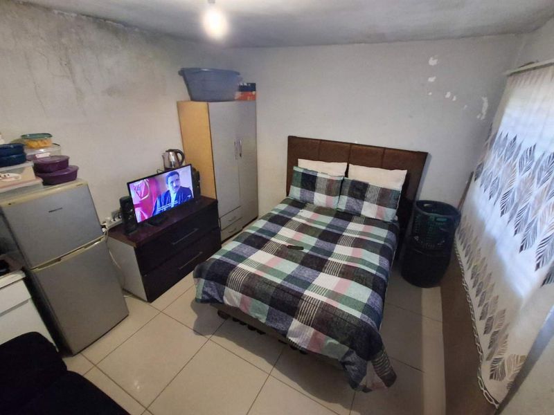 A compact bedroom featuring tiled flooring and visible wall surface deterioration requiring maintenance and cosmetic repair.