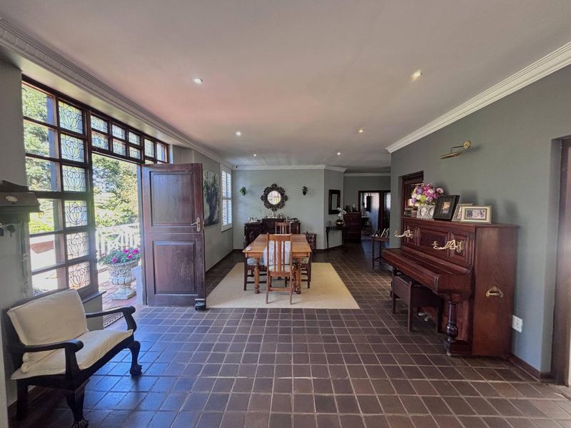Spacious living area featuring tiled flooring, crown molding, recessed lighting, and large leaded glass windows providing access to the outdoor patio.