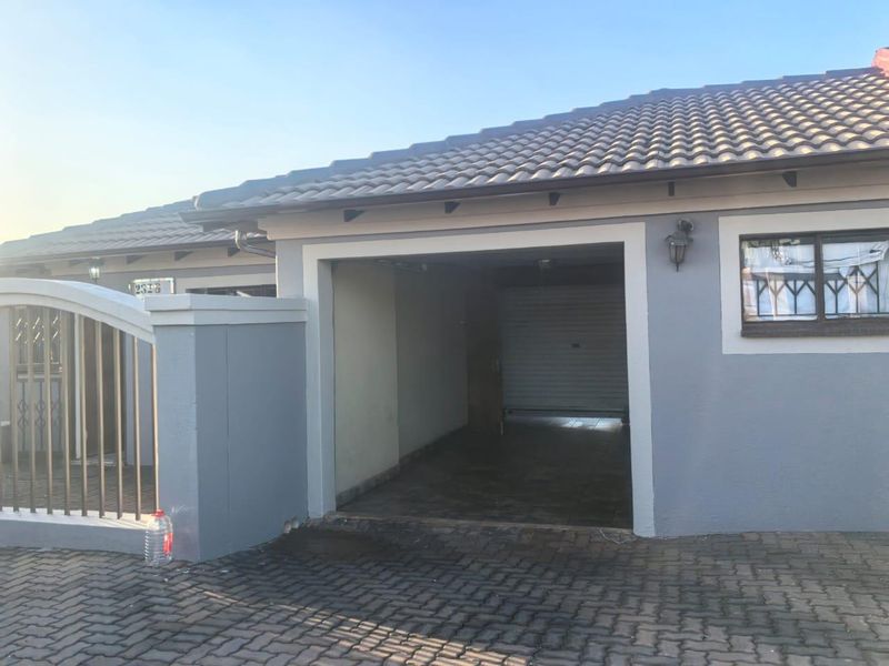 Front view of the property featuring a paved driveway, a single garage, and a secure gated entrance with tiled roofing.