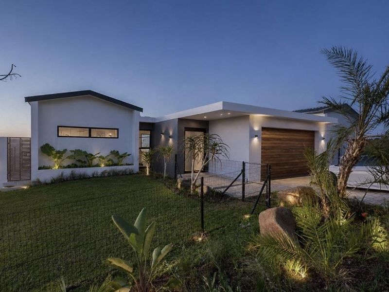 Modern single-story residence featuring a timber garage door, clean architectural lines, and professionally landscaped front garden with integrated exterior lighting.