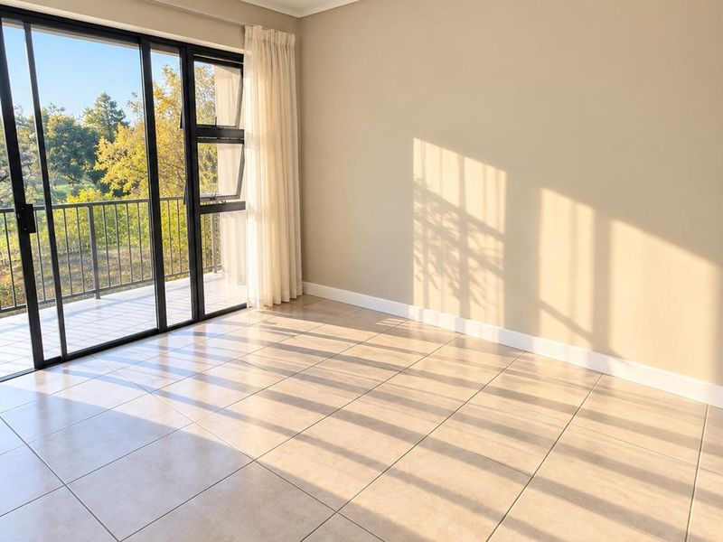 A bright, empty living area featuring neutral tiled flooring and large sliding glass doors that open onto a private balcony.