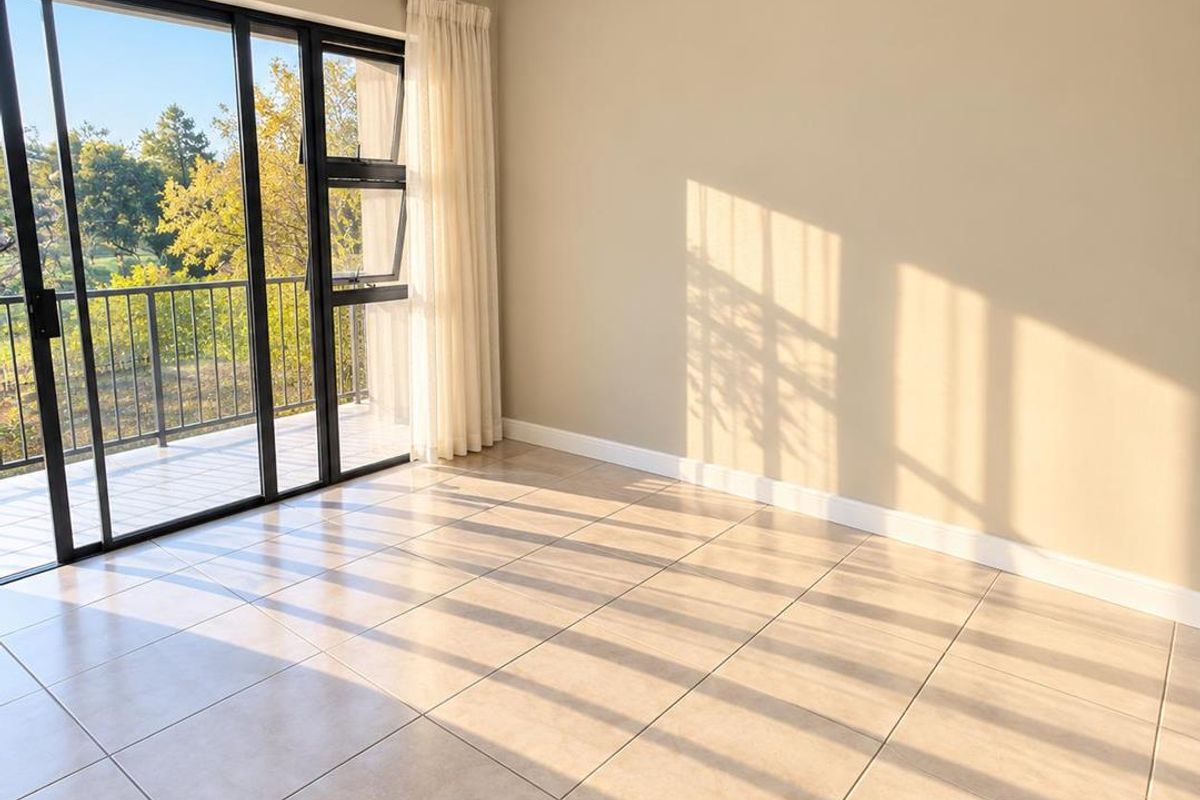 A bright, empty living area featuring neutral tiled flooring and large sliding glass doors that open onto a private balcony.