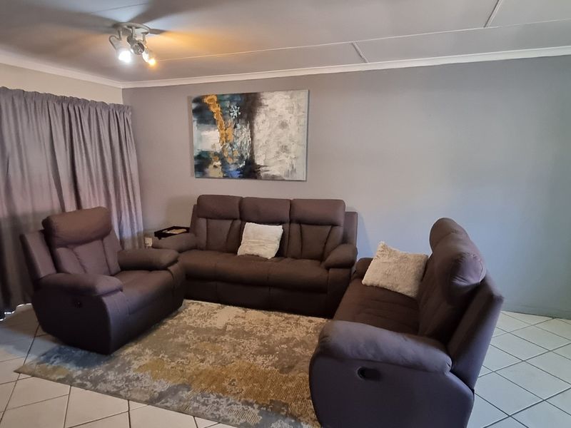 A living room area featuring tiled flooring, ceiling coving, and a sliding door leading to an outdoor space.