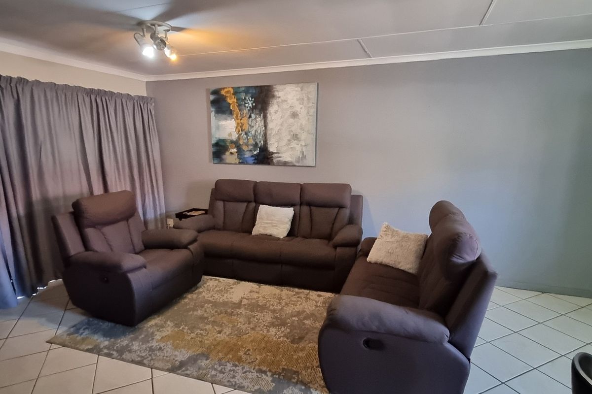 A living room area featuring tiled flooring, ceiling coving, and a sliding door leading to an outdoor space.