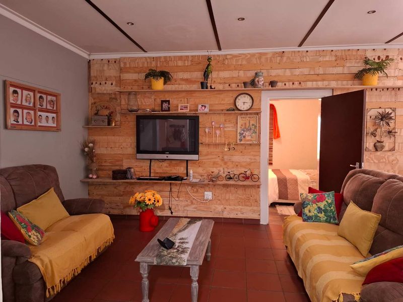 A living room featuring a timber-clad feature wall, tiled flooring, and recessed ceiling beams, providing a rustic aesthetic.