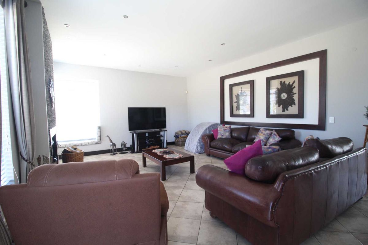 A spacious living room featuring tiled flooring, recessed ceiling lighting, and a decorative wall feature, providing a comfortable and functional family living space.