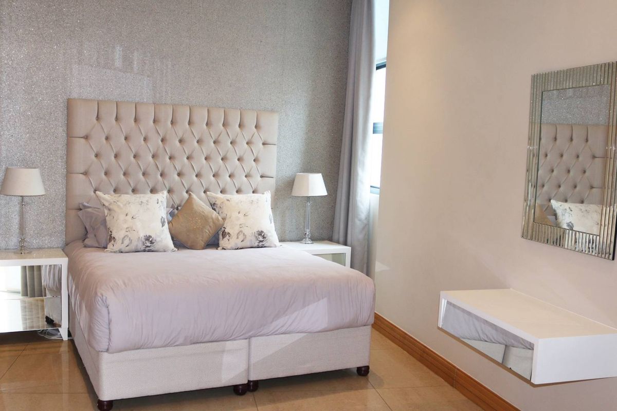 A well-maintained bedroom featuring tiled flooring, a textured feature wall, and a built-in floating vanity shelf.