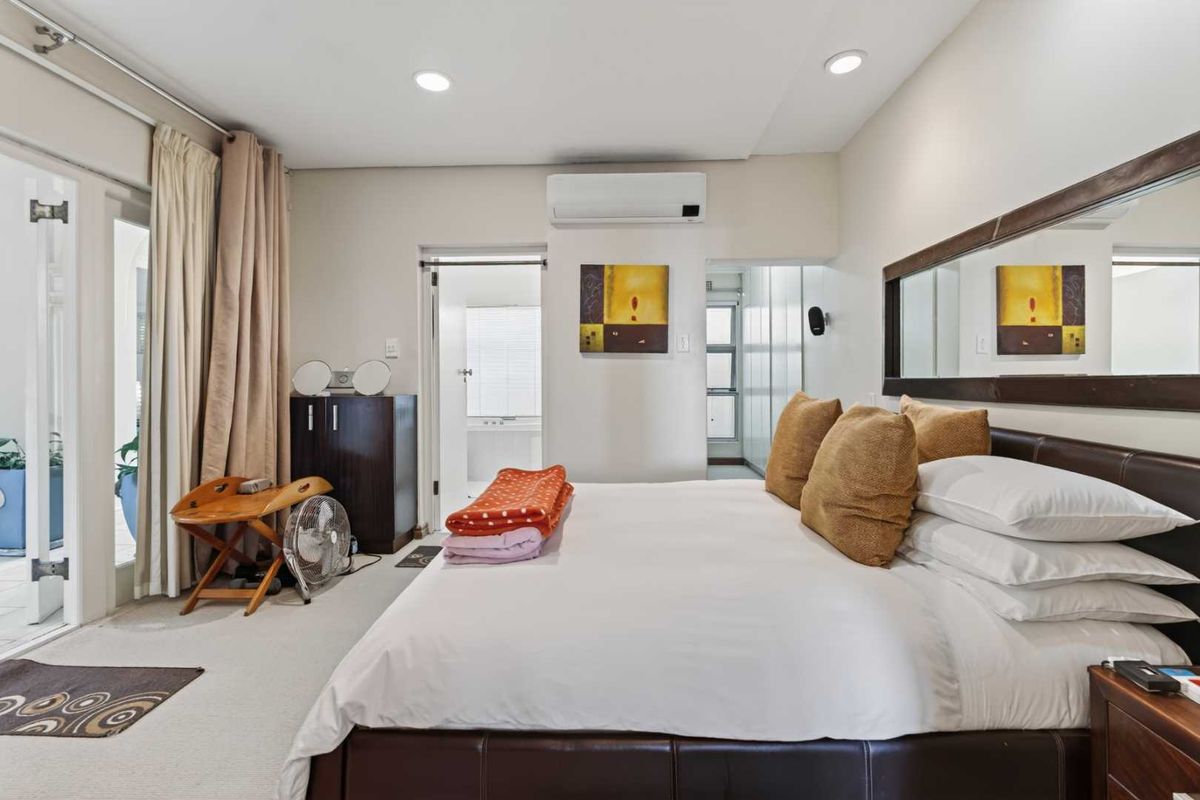 A well-maintained bedroom featuring neutral carpet, recessed lighting, a split-system air conditioner, and direct access to an outdoor area through a sliding glass door.