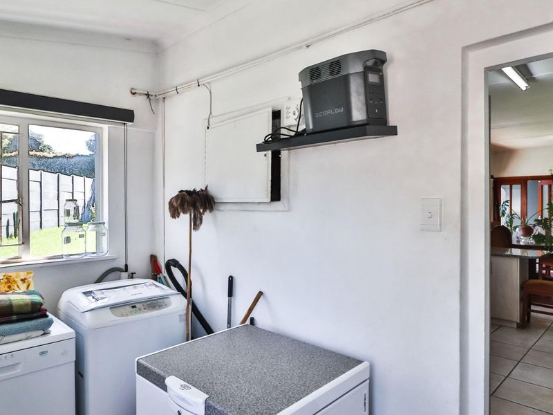 A functional laundry area featuring a window, surface-mounted electrical conduit, and access to the adjacent dining space.