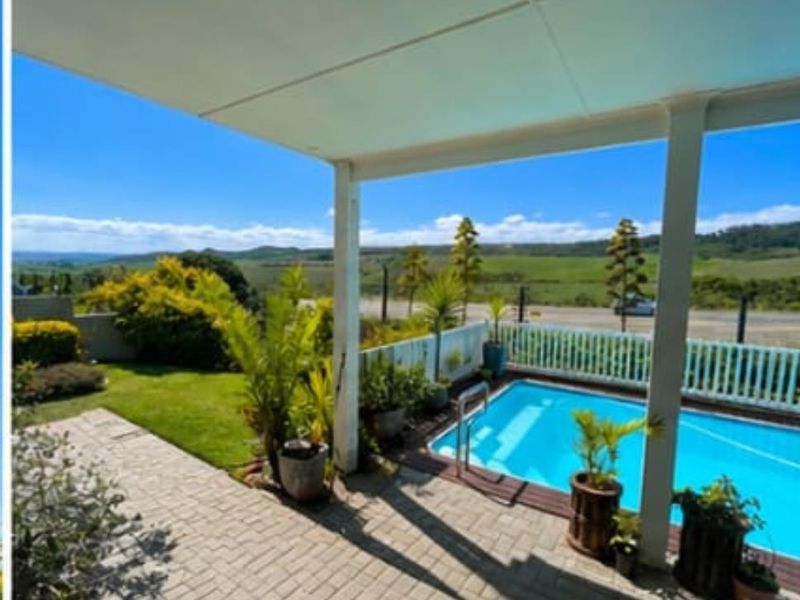 Outdoor entertainment area featuring a covered patio, paved terrace, and a swimming pool with scenic landscape views.