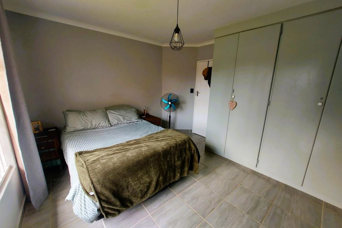 A bedroom featuring built-in cabinetry, tiled flooring, and a pendant light fixture.