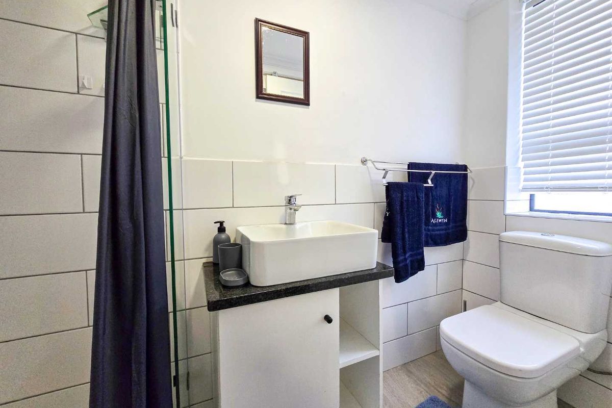 A modern bathroom featuring a vessel sink vanity, a glass-enclosed shower, and a white toilet, finished with clean white wall tiling.