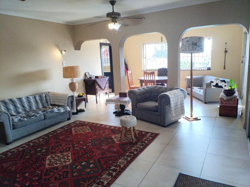 Spacious open-plan living and dining area featuring tiled flooring, arched architectural details, and a ceiling fan, offering a versatile layout for family living.