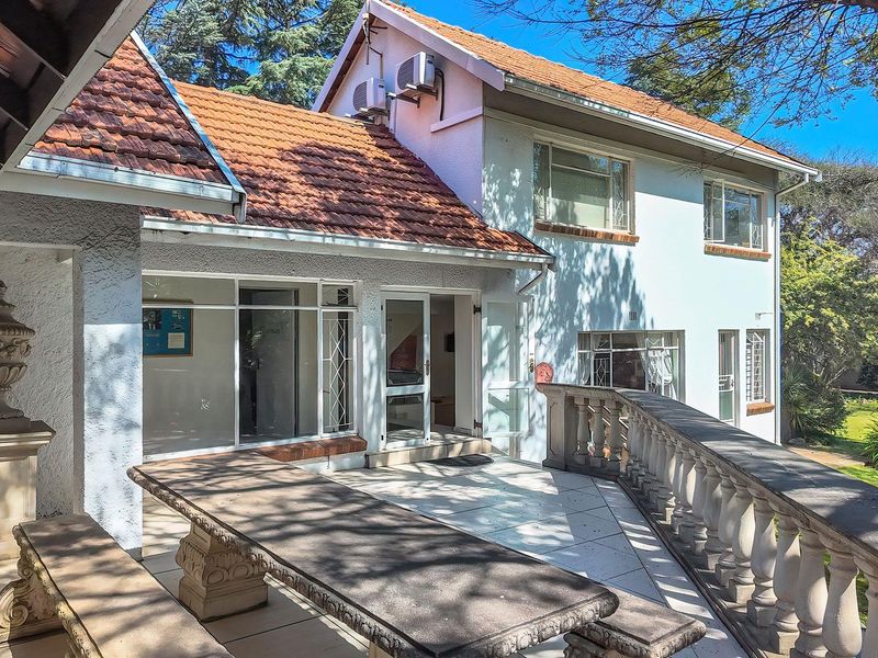 A spacious outdoor patio area featuring a stone balustrade, tiled flooring, and direct access to the office building interior through glass doors.