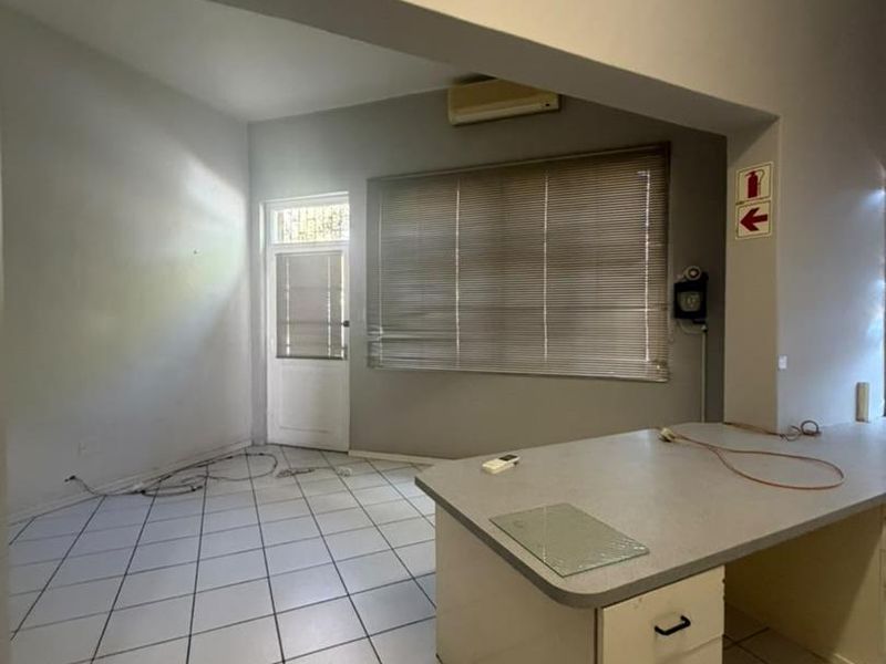 Open-plan space featuring tiled flooring, an archway, built-in desk cabinetry, and split-system air conditioning, suitable for a home office or living area.