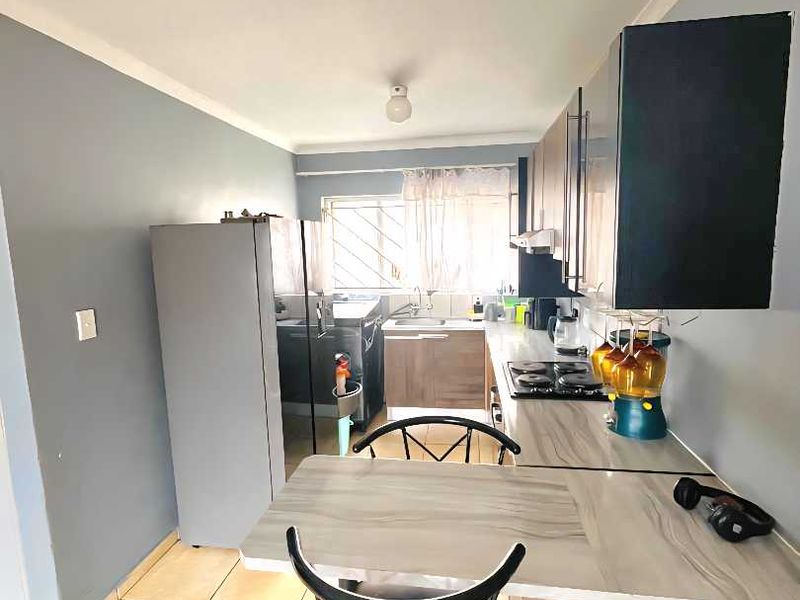 A functional kitchen featuring built-in cabinetry, a laminate countertop, a hob with extractor fan, and tiled flooring.
