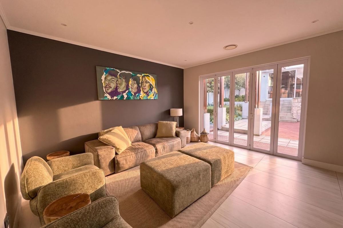 A bright and spacious living room featuring large glass folding doors that open onto an outdoor patio area, creating a seamless indoor-outdoor flow.