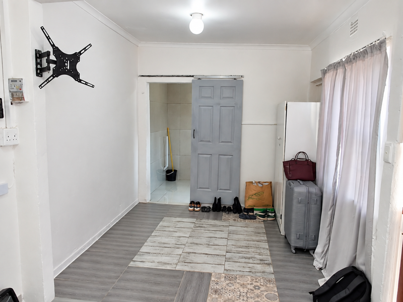 An entry area featuring laminate flooring, a sliding door leading to an adjacent space, and a wall-mounted TV bracket.
