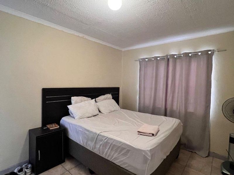 A bedroom featuring tiled flooring and a textured ceiling, currently requiring cosmetic updates to improve the overall condition and appeal of the space.