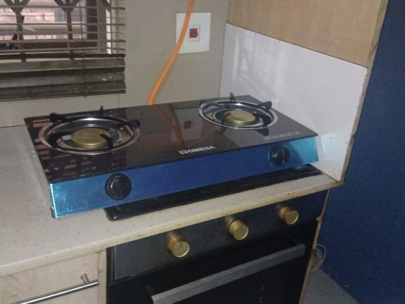 A kitchen area featuring a built-in oven and a gas hob, with visible unfinished wall sections and exposed wiring near the countertop.