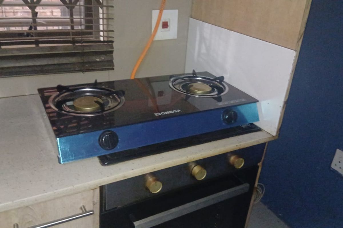 A kitchen area featuring a built-in oven and a gas hob, with visible unfinished wall sections and exposed wiring near the countertop.