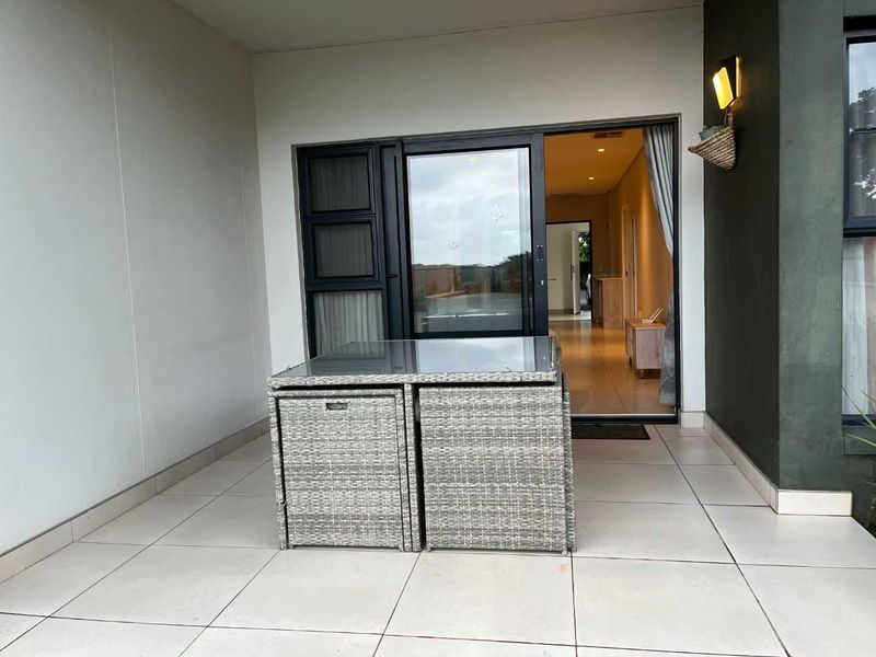 A covered patio area featuring tiled flooring and a large sliding glass door providing access to the interior living space.