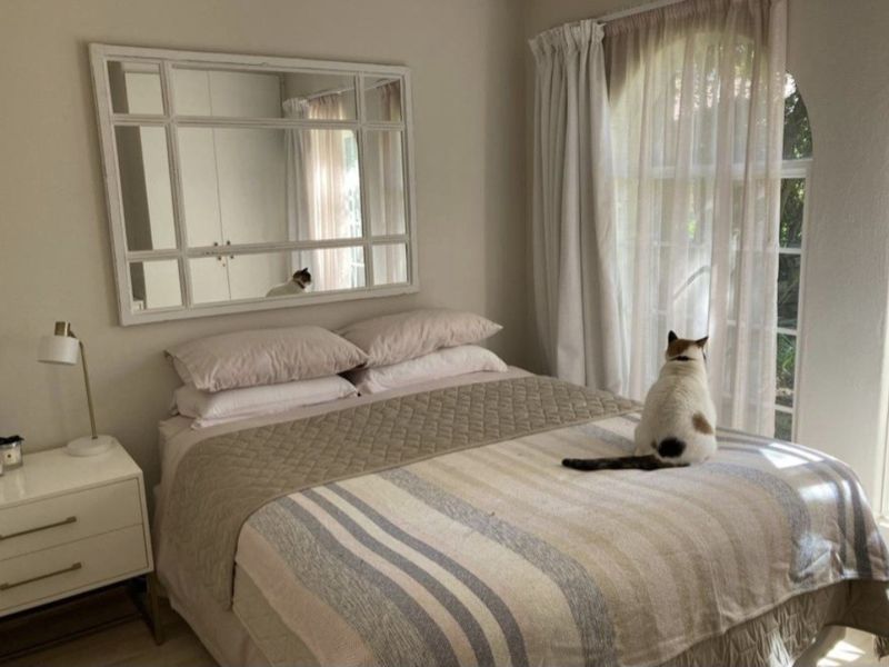 A cozy bedroom featuring an arched window with natural light and built-in cupboard storage.
