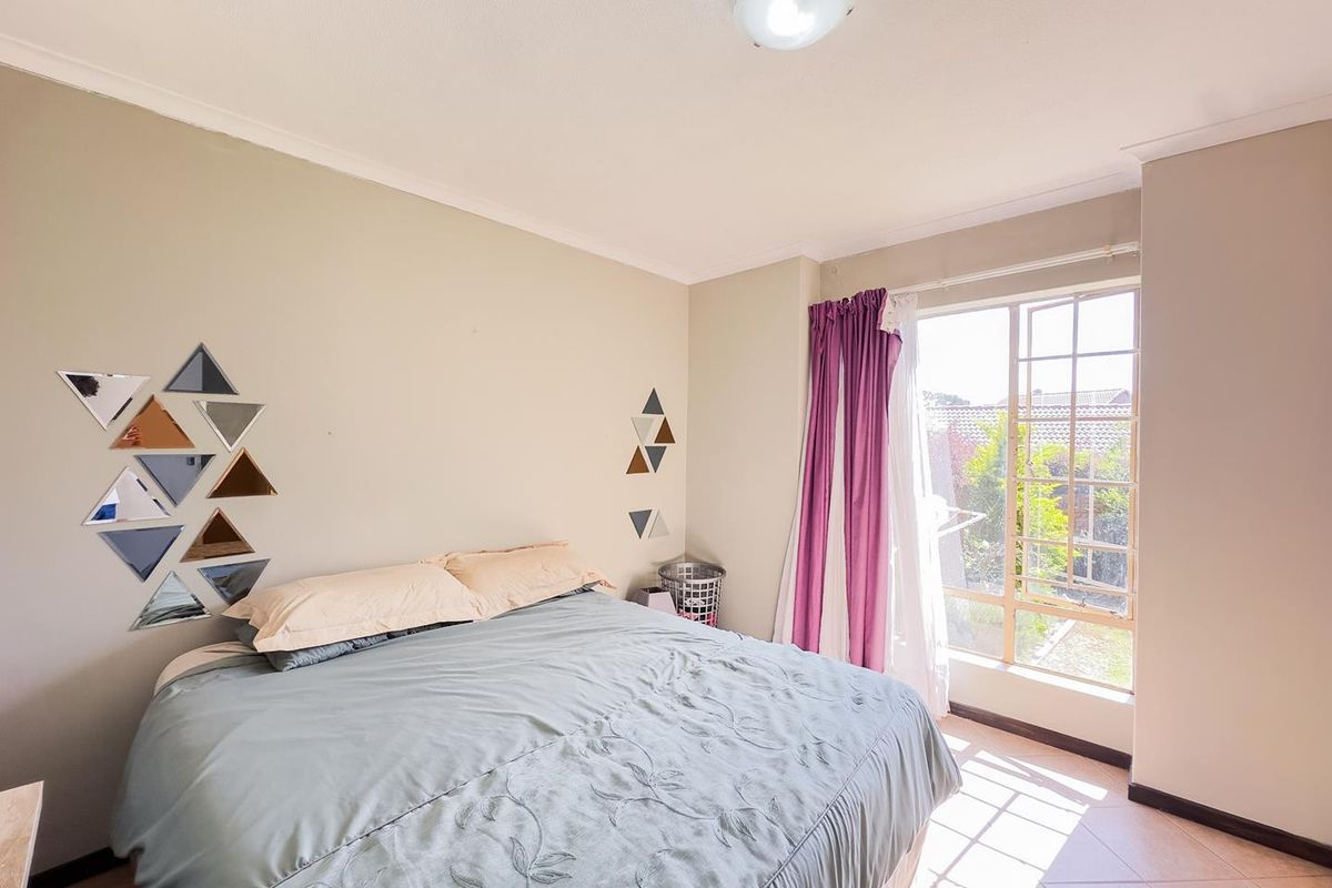 A bedroom featuring tiled flooring and a large window that allows for natural light, providing a functional and comfortable living space.