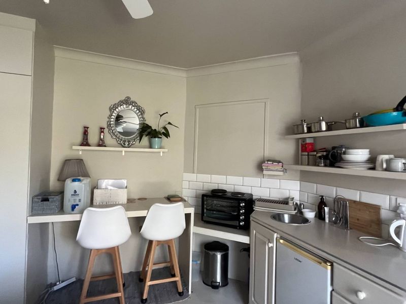 Compact kitchen area featuring subway tile backsplash, floating shelving, built-in cabinetry, and a convenient integrated desk space.