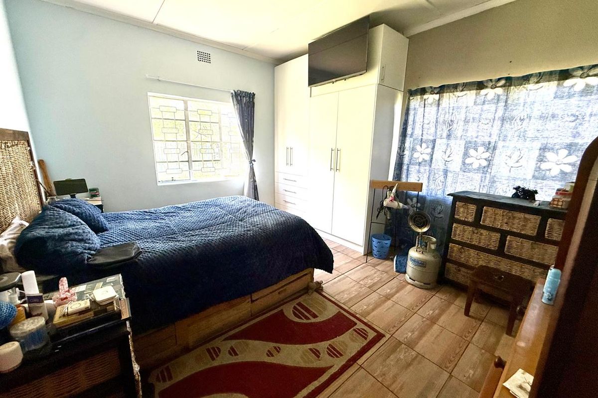 A functional bedroom featuring built-in cupboards, tiled flooring, and security burglar bars on the window.