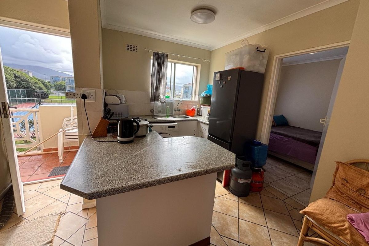 Compact kitchen featuring a breakfast bar, tiled flooring, and direct access to a private balcony, offering a functional layout for apartment living.