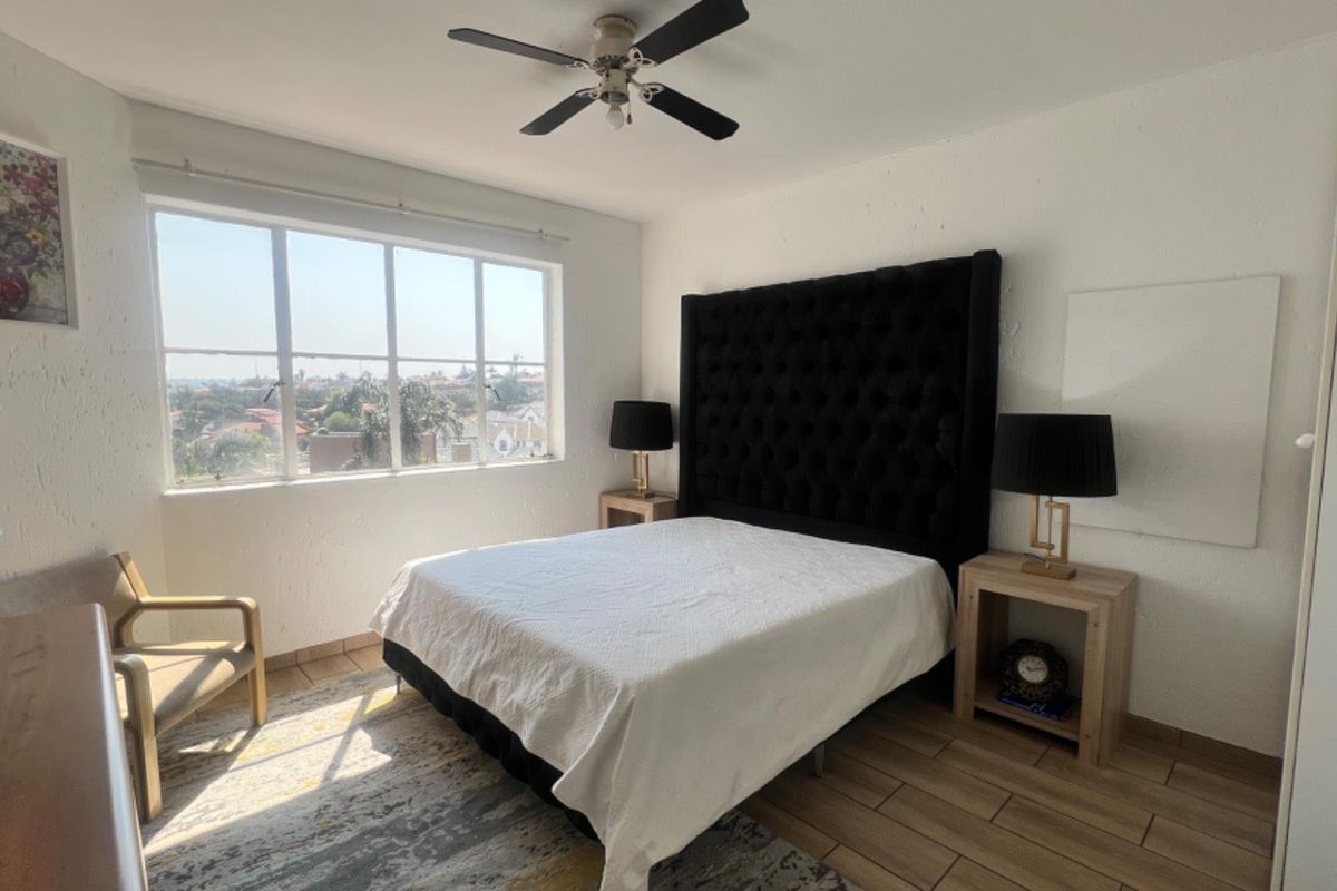 A bright bedroom featuring large windows with neighborhood views, tiled flooring, and a ceiling fan.