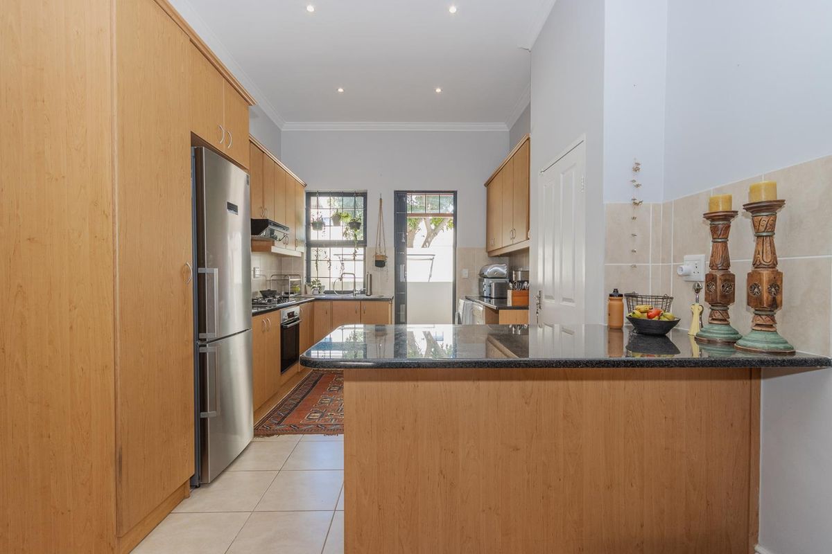 A functional kitchen featuring light wood cabinetry, granite countertops, a gas hob, and an integrated oven, with direct access to an outdoor area.