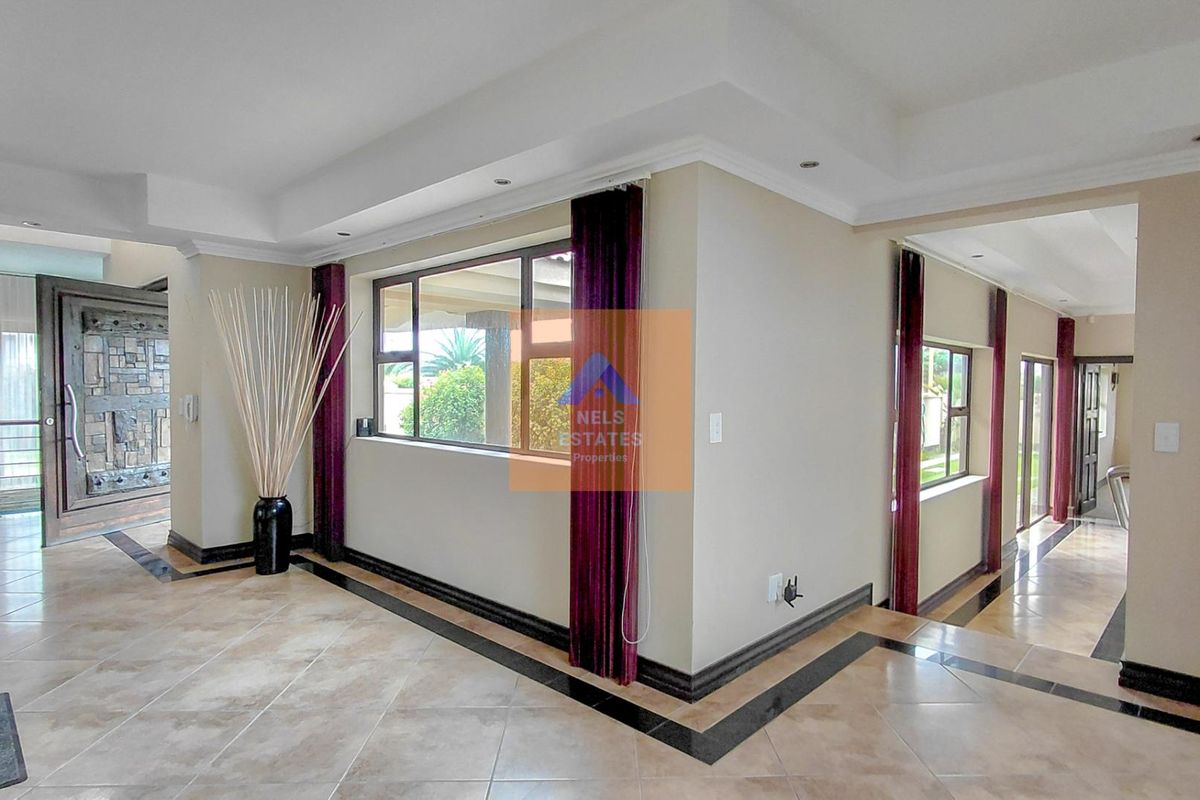 Spacious living area featuring tiled floors with decorative borders, recessed ceiling lighting, and a distinctive solid wood front door.