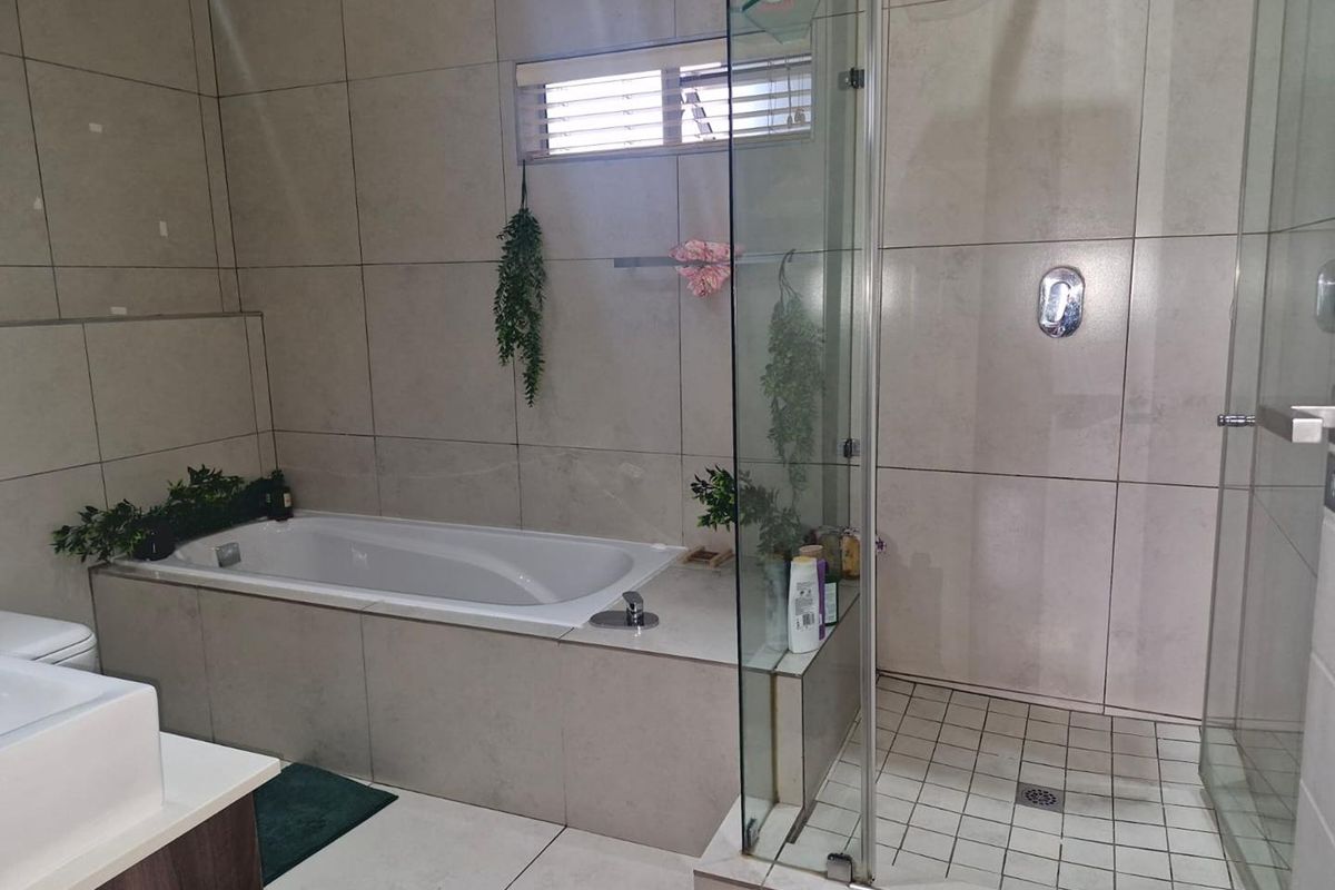 Modern bathroom featuring a built-in bathtub, a separate glass-enclosed shower, and large format wall tiles.