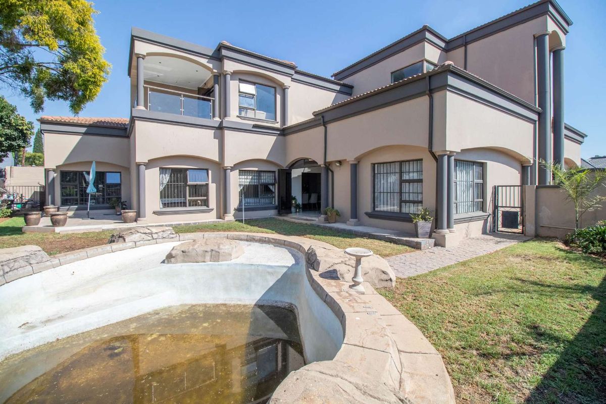 Rear view of a multi-story residence featuring a swimming pool, covered patio, and landscaped garden area.