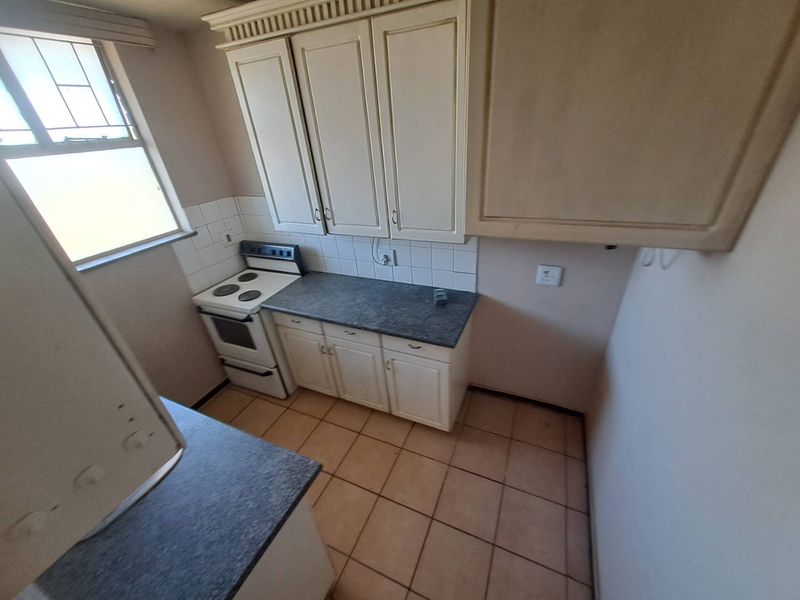 A functional kitchen featuring built-in cabinetry, laminate countertops, a freestanding stove, and tiled flooring, offering a clean space ready for modernization.
