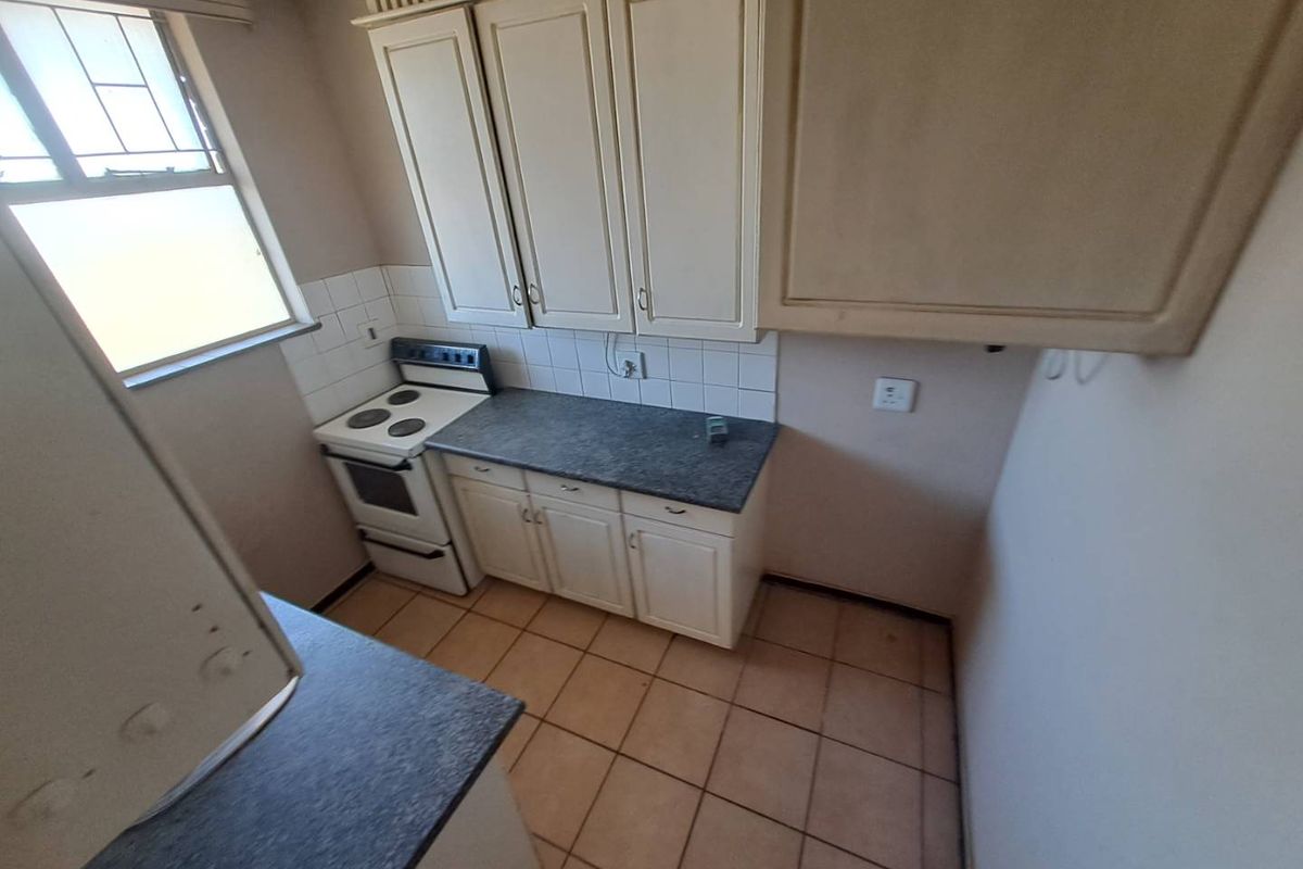 A functional kitchen featuring built-in cabinetry, laminate countertops, a freestanding stove, and tiled flooring, offering a clean space ready for modernization.